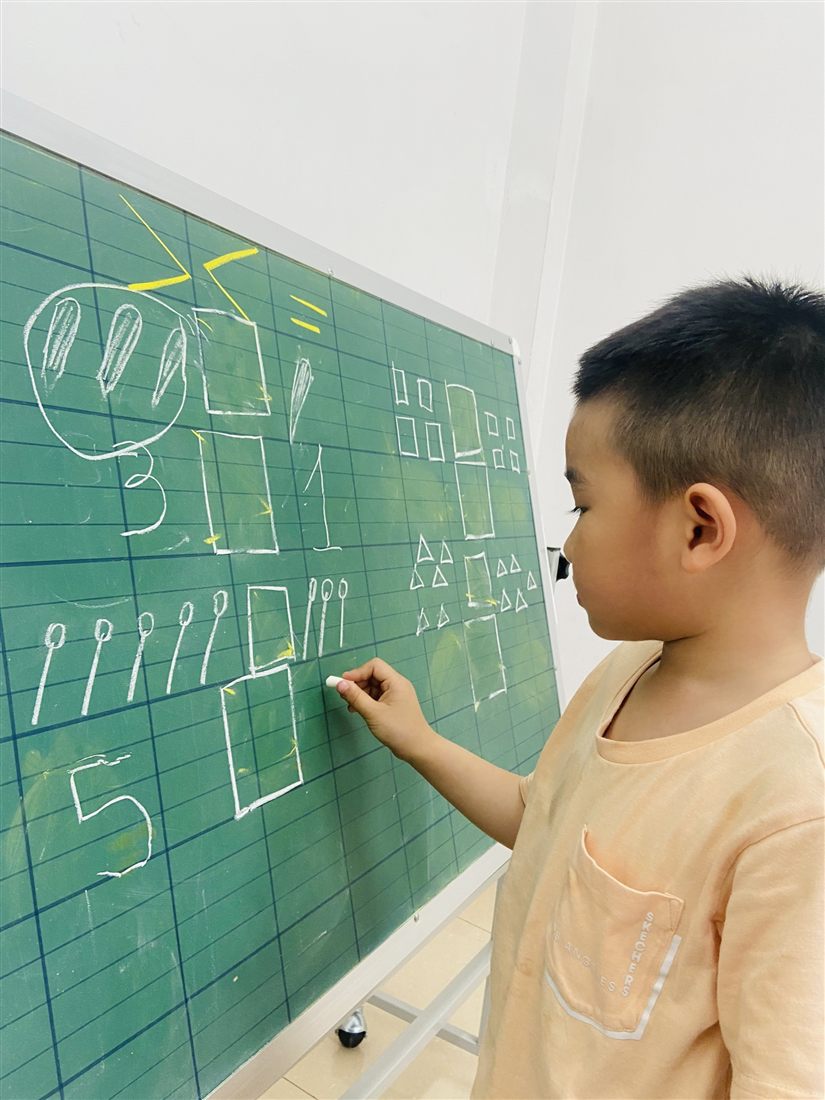 Trẻ tập viết số trên bảng trong lớp tiền tiểu học